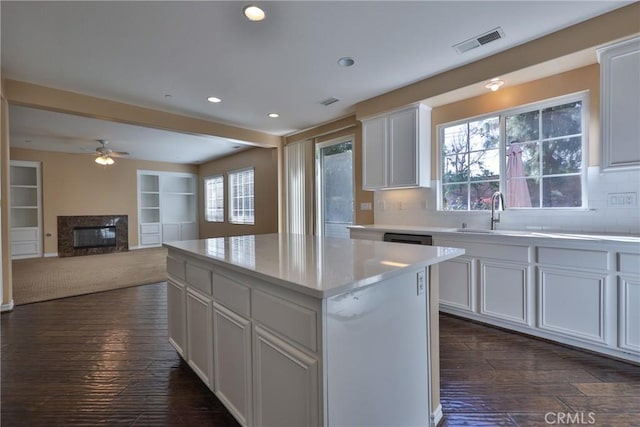 kitchen with a fireplace, a sink, visible vents, light countertops, and dark wood-style floors