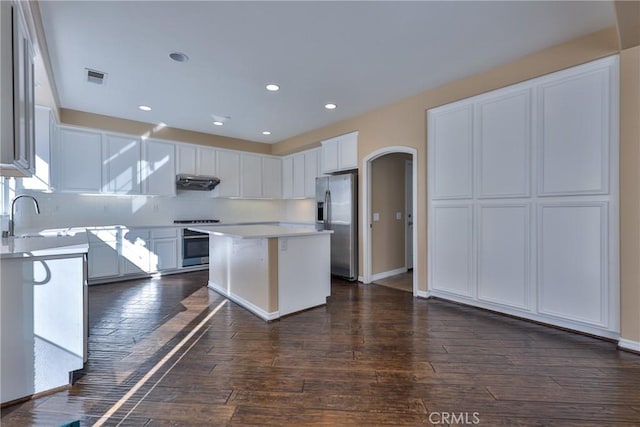 1230 Cantania Dr, Redlands, CA 92374 - kitchen featuring stainless steel fridge with ice dispenser, stove, arched walkways, dark wood-type flooring, and light countertops