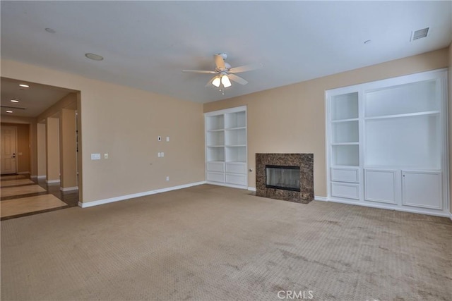 unfurnished living room with carpet floors, built in shelves, visible vents, and baseboards