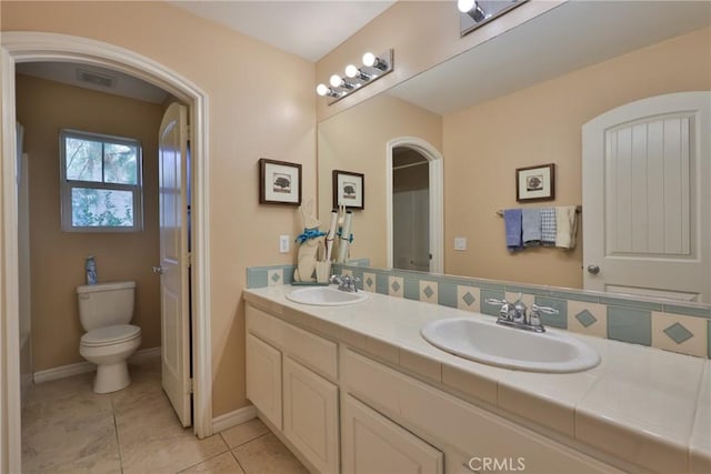 full bath featuring visible vents, double vanity, a sink, and toilet