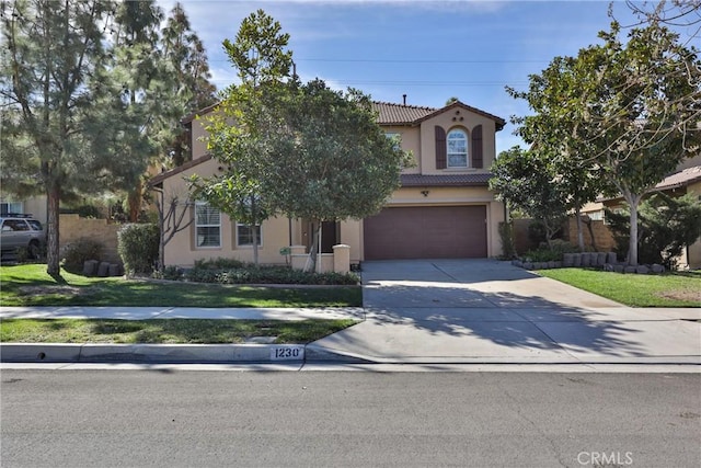 mediterranean / spanish house with an attached garage, driveway, a tiled roof, stucco siding, and a front lawn