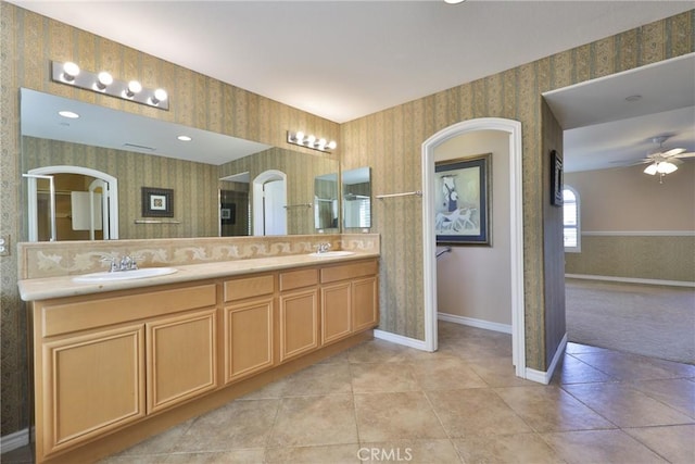 bathroom with a ceiling fan, tile patterned floors, a sink, and wallpapered walls