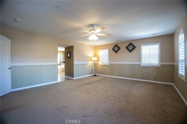 carpeted spare room featuring ceiling fan, baseboards, and wallpapered walls