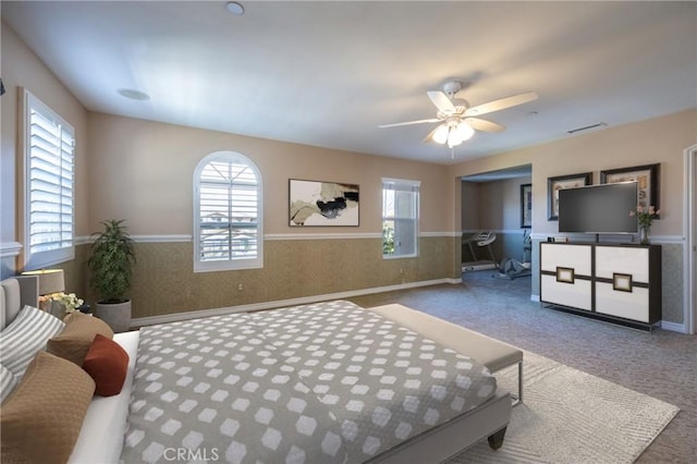 carpeted bedroom with multiple windows, wainscoting, and wallpapered walls