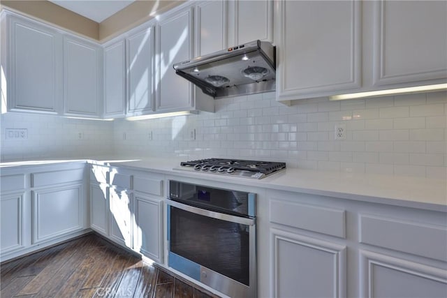 kitchen with dark wood-style floors, stainless steel appliances, light countertops, backsplash, and under cabinet range hood