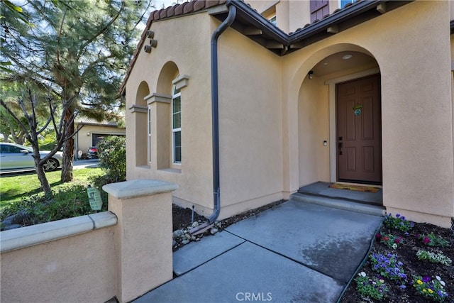 entrance to property featuring a tile roof and stucco siding