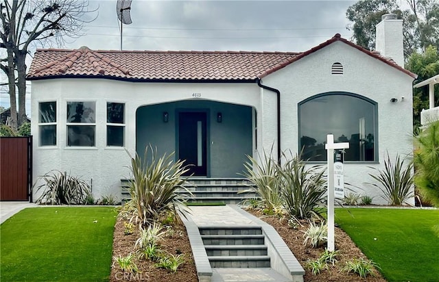 mediterranean / spanish house featuring stucco siding, a front lawn, and a tile roof