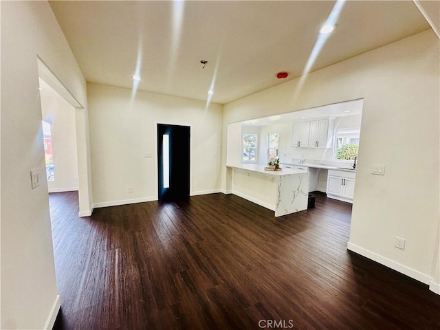 unfurnished living room featuring recessed lighting, dark wood-type flooring, and baseboards