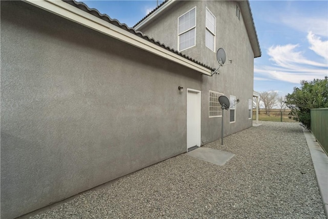 view of home's exterior featuring a garage, a tile roof, fence, and stucco siding