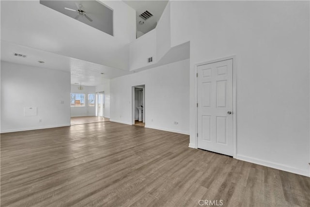 unfurnished living room with baseboards, ceiling fan, visible vents, and wood finished floors