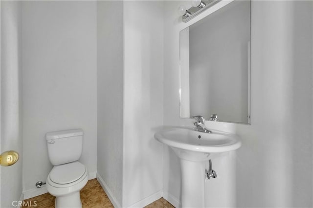 half bath featuring toilet and baseboards