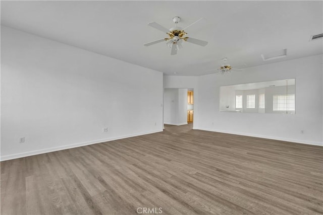 unfurnished room with ceiling fan, wood finished floors, visible vents, and baseboards