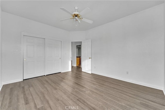unfurnished bedroom with a closet, ceiling fan, baseboards, and wood finished floors