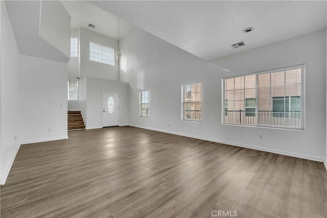 unfurnished living room with dark wood-style floors, visible vents, and baseboards