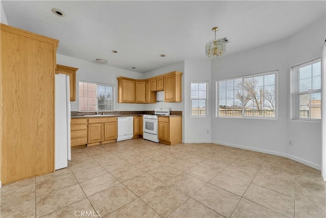 kitchen with a healthy amount of sunlight, white appliances, baseboards, and a sink
