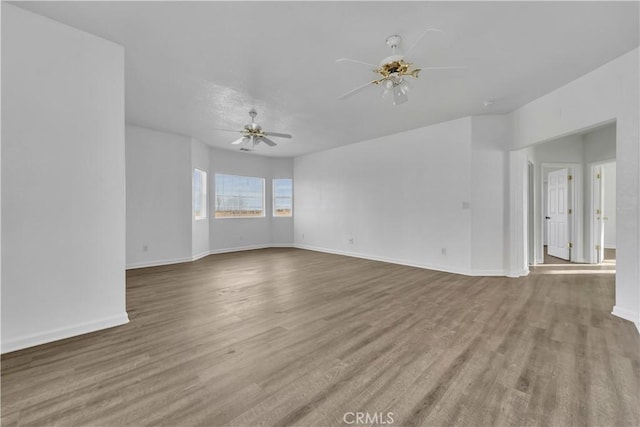 empty room featuring ceiling fan, baseboards, and wood finished floors