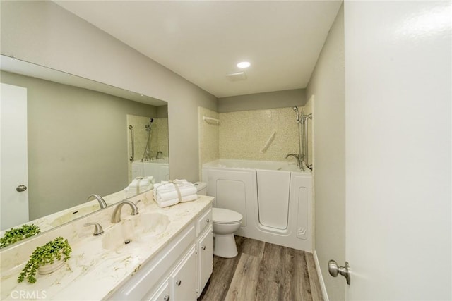 bathroom with toilet, wood finished floors, vanity, independent washer and dryer, and a bath