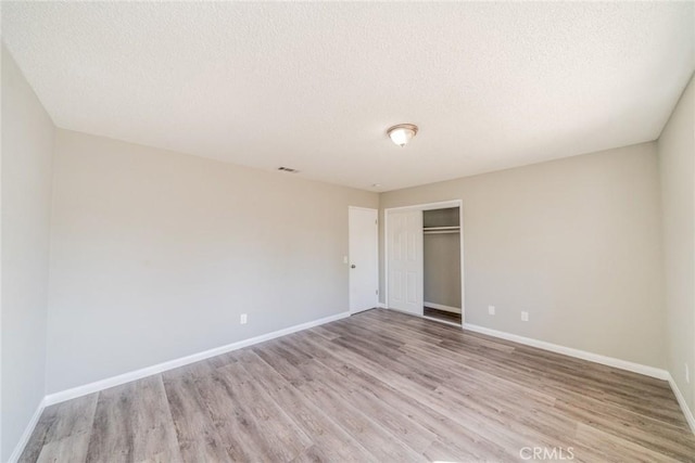 unfurnished bedroom with baseboards, a closet, and light wood-style floors