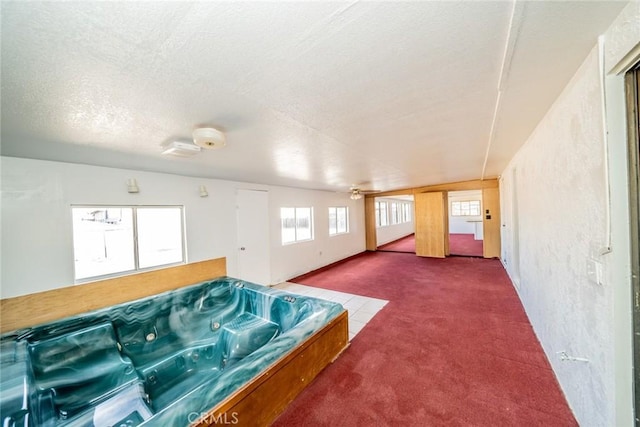 rec room featuring a textured ceiling, carpet floors, and a hot tub