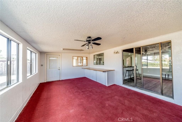 unfurnished living room featuring a ceiling fan, carpet, and a textured ceiling