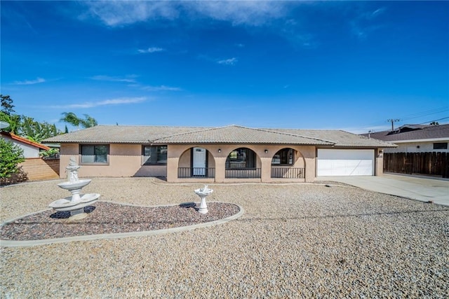 view of front facade featuring driveway, a garage, a tiled roof, fence, and stucco siding