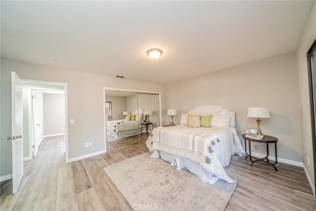 bedroom with light wood-style floors, a closet, visible vents, and baseboards