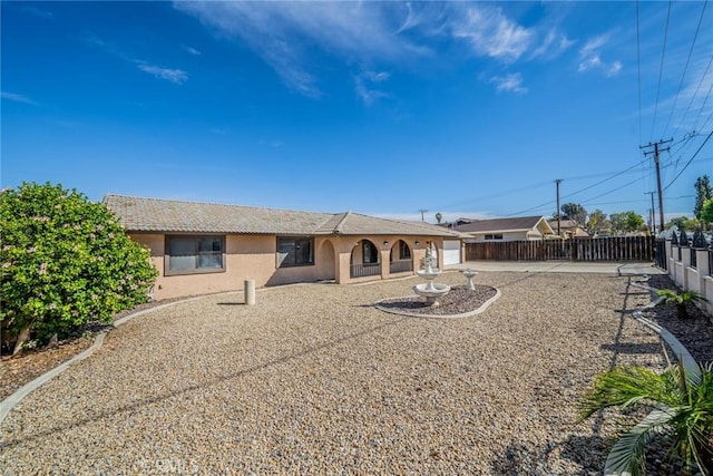 back of property featuring a tile roof, fence, and stucco siding