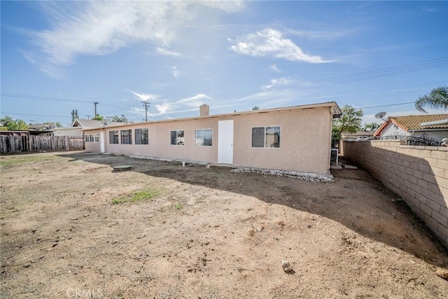 back of house featuring fence and stucco siding