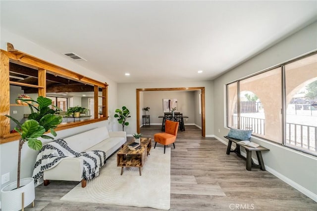 living area with plenty of natural light, visible vents, light wood-style flooring, and baseboards