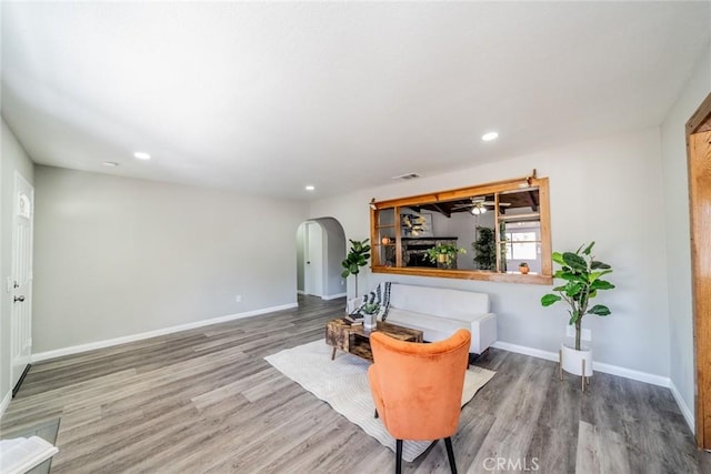 sitting room featuring arched walkways, recessed lighting, baseboards, and wood finished floors