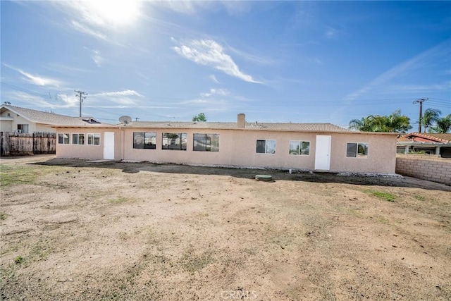 rear view of property with fence and stucco siding