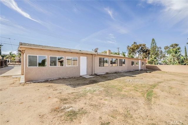 back of property with fence and stucco siding