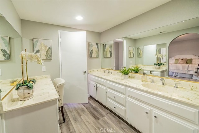 ensuite bathroom with double vanity, ensuite bathroom, a sink, and wood finished floors