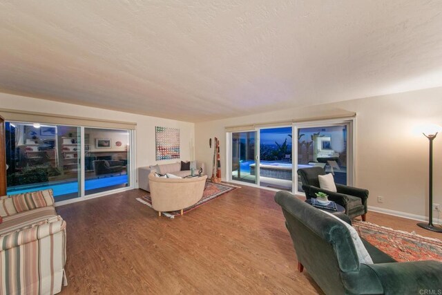 living area with a textured ceiling, baseboards, and wood finished floors