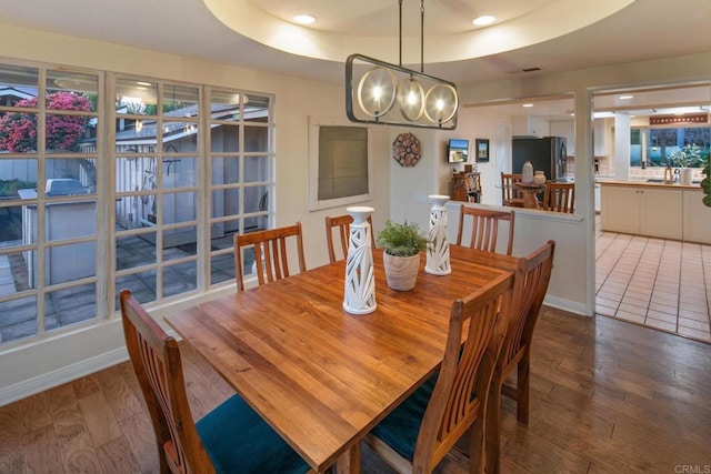 dining space featuring baseboards, a raised ceiling, hardwood / wood-style flooring, and recessed lighting