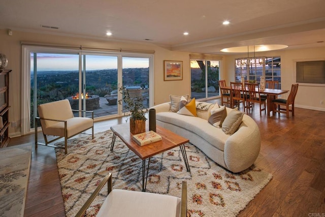 living room featuring baseboards, visible vents, ornamental molding, wood finished floors, and recessed lighting