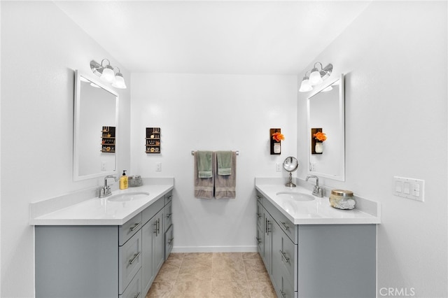 full bathroom with two vanities, a sink, and baseboards