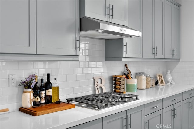 kitchen with stainless steel gas stovetop, gray cabinets, light countertops, and under cabinet range hood