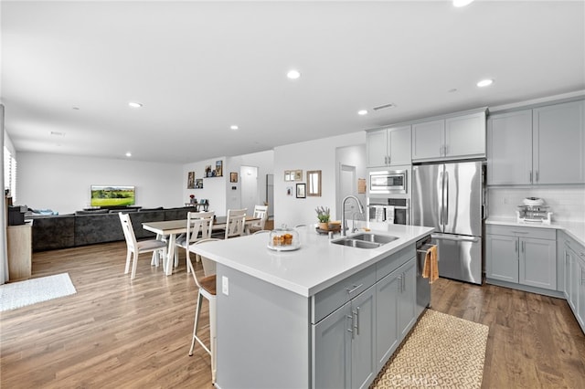 kitchen featuring a sink, appliances with stainless steel finishes, wood finished floors, and gray cabinets