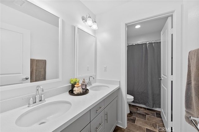 bathroom featuring visible vents, a sink, toilet, and double vanity