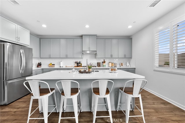 kitchen featuring dark wood-style flooring, light countertops, backsplash, gray cabinetry, and freestanding refrigerator