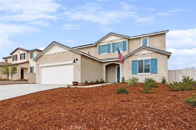 traditional-style home with a garage, concrete driveway, fence, and stucco siding