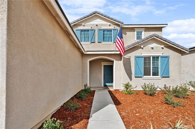 doorway to property featuring a tile roof and stucco siding