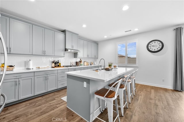 kitchen featuring a sink, wood finished floors, visible vents, gray cabinets, and stainless steel gas stovetop