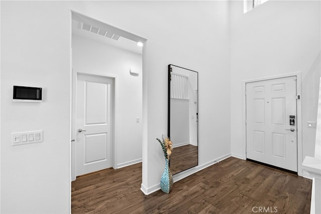 entrance foyer featuring dark wood-style floors, a high ceiling, visible vents, and baseboards