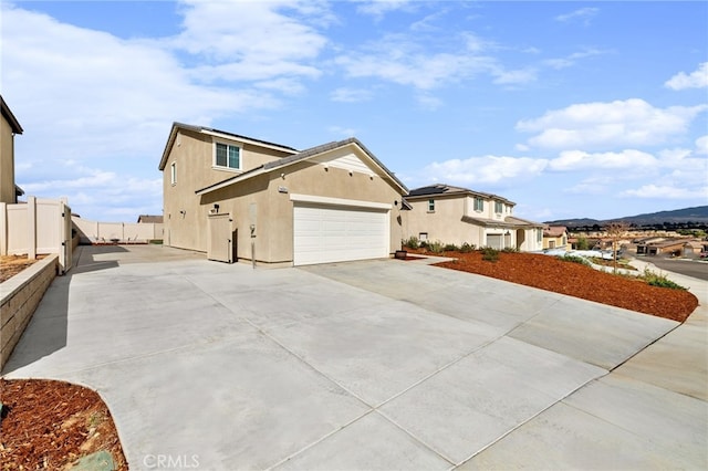 view of front facade with a garage, concrete driveway, fence, and stucco siding