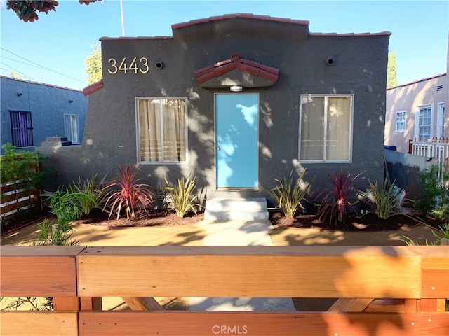 mediterranean / spanish home with fence and stucco siding