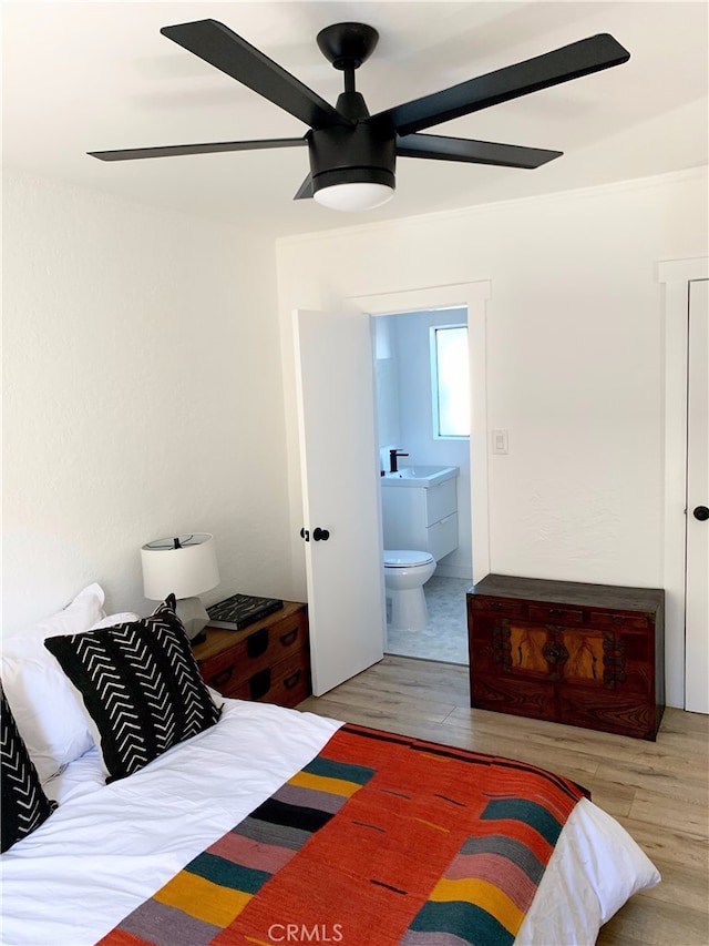 bedroom featuring a sink, ensuite bath, ceiling fan, and wood finished floors