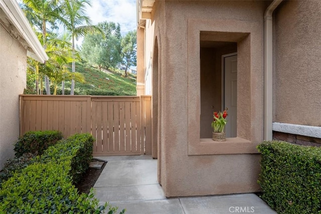 doorway to property with fence and stucco siding