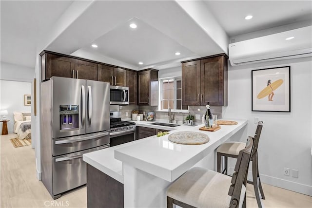 309 W Avenida Palizada, San Clemente, CA 92672 - kitchen featuring dark brown cabinetry, a sink, a kitchen breakfast bar, appliances with stainless steel finishes, and decorative backsplash